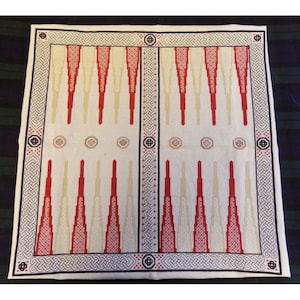 May include: A white backgammon board with red and beige triangular points. The board has a black and white Celtic knot border and decorative center medallions. The game board is designed for two players.