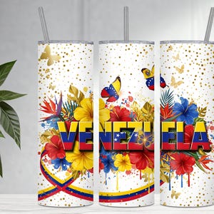 May include: A white tumbler with a design featuring the word "VENEZUELA" in red, yellow, and blue, surrounded by colorful flowers and butterflies. The design includes the Venezuelan flag colors and gold accents.