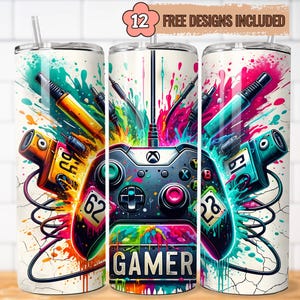 May include: A set of three white stainless steel tumblers with a colorful gamer design. The design features a video game controller, game accessories, and the word "GAMER". The tumblers include a straw and the text "12 FREE DESIGNS INCLUDED".