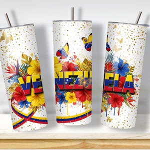 May include: Three white insulated tumblers with the word "VENEZUELA" in red, yellow, and blue, the colors of the Venezuelan flag. The tumblers feature floral and butterfly designs, with gold accents and a straw.