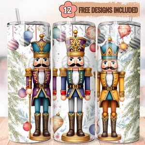 Peut inclure: Trois gobelets sur le thème de Noël avec des motifs de casse-noisettes. Chaque gobelet présente un casse-noisettes différent dans un uniforme coloré, avec des ornements de Noël et des branches de pin en arrière-plan. Le texte "12 FREE DESIGNS INCLUDED" est en haut.