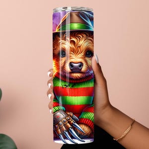 May include: A tall, stainless steel tumbler featuring a cartoon dog dressed as Freddy Krueger. The dog wears a striped green and red sweater, a brown hat, and a metal glove with sharp claws. The background has a purple and green night sky.