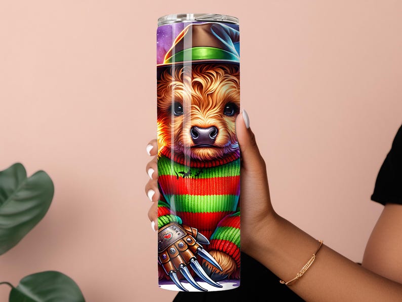 May include: A tall, stainless steel tumbler featuring a cartoon dog dressed as Freddy Krueger. The dog wears a striped green and red sweater, a brown hat, and a metal glove with sharp claws. The background has a purple and green night sky.