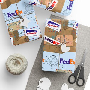 May include: Three gift-wrapped packages with brown paper and blue accents, adorned with FedEx logos and tags. Each package is tied with twine and decorated with star and heart-shaped embellishments. A ball of twine and scissors are also visible.