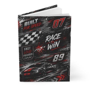Peut inclure: Un carnet à couverture rigide avec un graphisme sur le thème de la course en noir, gris et rouge. La couverture présente une voiture de sport noire, un drapeau à damier et le texte BUILT FOR SPEED, RACE TO WIN, FAST LOUD FOCUSED, 07 et 89.