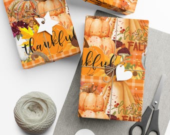 Op de afbeelding: Drie ingepakte cadeaus met herfstthema's van pompoenen en bladeren. De cadeaus zijn vastgebonden met touw en versierd met stervormige en hartvormige labels. Een bol touw, een schaar en blanco labels zijn ook zichtbaar.