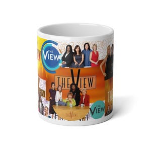 Könnte beinhalten: Weißer Keramikbecher mit dem Schriftzug "THE VIEW" und Bildern der Moderatoren der Show. Der Becher hat ein helles, farbenfrohes Design, wobei das Logo der Show deutlich sichtbar ist. Ideal für Fans der Talkshow.