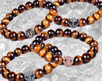 May include: Three tiger's eye beaded bracelets with silver and black panther head charms. The charms have sparkling rhinestones.