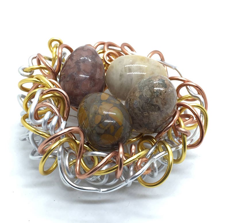 May include: A wire nest made of silver, copper, and gold wire with four colorful agate stones inside.