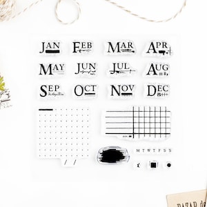 May include: A set of 12 clear rubber stamps featuring the months of the year in a vintage font. The stamps also include a grid, a dotted grid, a brush stroke, and the days of the week.
