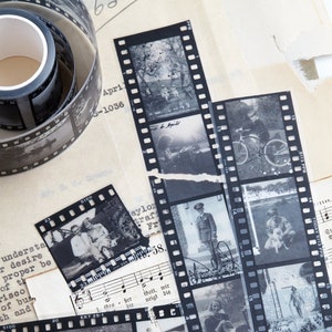 May include: A collection of black and white photographs on strips of film. The photos show various scenes, including people, landscapes, and objects. The film strips are arranged in a random pattern on a white surface.