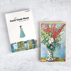 May include: A postcard set featuring the art of Claude Monet. The set includes a box with an illustration of a woman in a blue dress and a postcard with a floral still life. The box reads "The Classic Claude Monet POSTCARD SET."