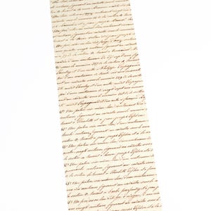 May include: A close-up of a rolled up piece of paper with handwritten text in brown ink on a cream-colored background. The text is in French and is difficult to read.