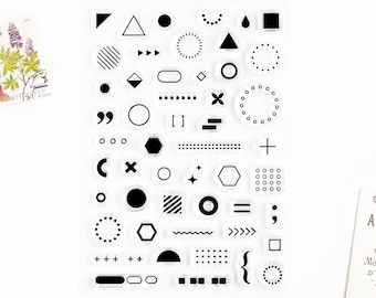 May include: A clear sheet of transparent stamps with black geometric shapes, lines, and symbols. The stamps include circles, squares, triangles, stars, plus signs, and more.