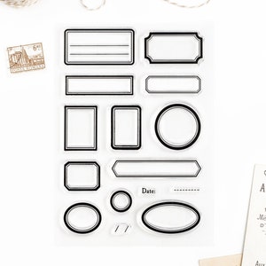 May include: Clear stamp sheet with 14 different frame and label shapes. The shapes include circles, ovals, rectangles, and squares. The sheet is designed for crafting and scrapbooking.