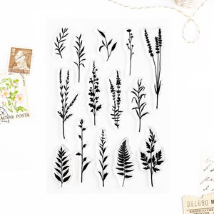 May include: A clear sheet of transparent stamps featuring 14 different black silhouette designs of various grasses and ferns.