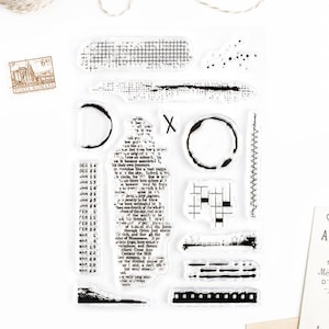 Peut inclure: Une feuille transparente de tampons avec des motifs d'encre noire. Les motifs comprennent des cercles, des lignes, des grilles et un texte.