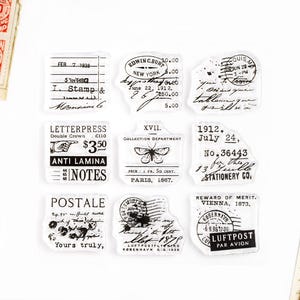 May include: A set of ten vintage-style rubber stamps featuring various designs, including a butterfly, a letterpress, a postal stamp, and a reward of merit. The stamps are black and white and have a distressed look.