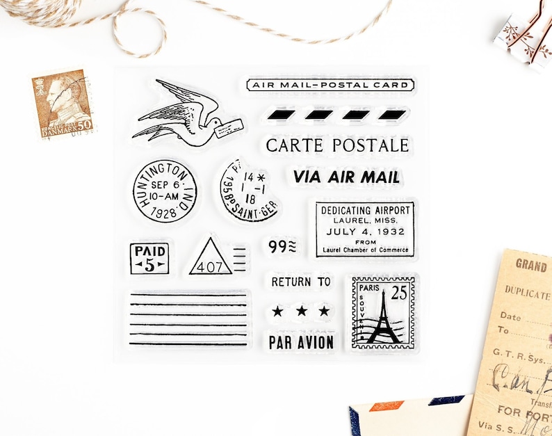 Peut inclure: Un ensemble de tampons en caoutchouc de style vintage repr&eacute;sentant divers motifs li&eacute;s au courrier a&eacute;rien et aux services postaux. Les tampons comprennent un oiseau en vol, un cachet postal, un timbre avec la tour Eiffel et du texte qui dit "Air Mail-Postal Card", "Carte Postale", "Via Air Mail", "99&cent;", "Return To", "Par Avion", et "Paid -5-".