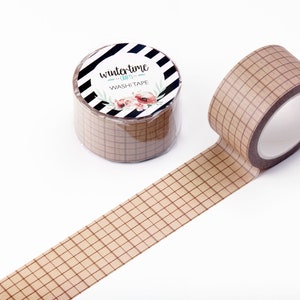 May include: A roll of brown washi tape with a grid pattern. The tape is unrolled and the roll is visible with a label that says "wintertime - crafty - washi tape".