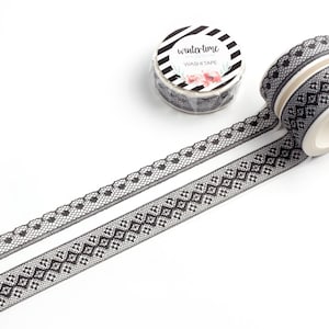 May include: Two rolls of black and white washi tape with lace patterns. The tape is labeled "wintertime washi tape".
