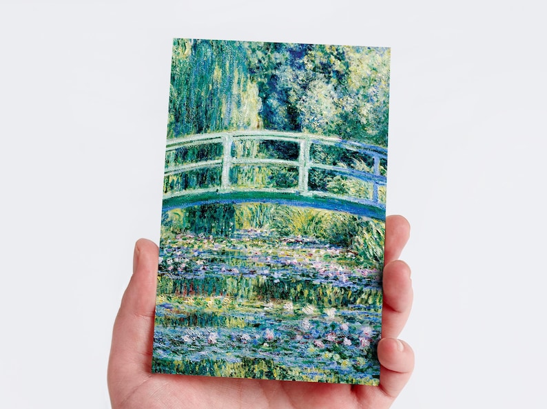 May include: A postcard depicting a painting of a Japanese bridge over a pond with water lilies. The artwork uses green, blue, and purple hues. The bridge has a white railing and arches over the water, reflecting in the pond.