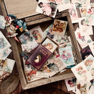 May include: A wooden box filled with vintage-style postcards featuring children. The box is open and the postcards are arranged in a random pattern. The box is labeled "CHILDHOOD".