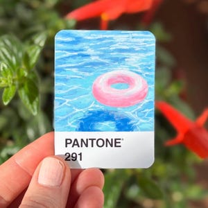 Puede incluir: Una pegatina rectangular con una pintura de un flotador inflable rosa flotando en una piscina azul. La pegatina tiene el código de color Pantone 291.