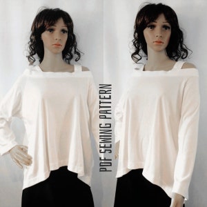 May include: White long-sleeved top with a cold shoulder design. The top has a relaxed fit and a slightly asymmetrical hemline. The model is wearing black trousers.