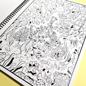 K&ouml;nnte beinhalten: Eine Schwarzwei&szlig;illustration einer Unterwasserszene mit Korallenriffen, Fischen und anderen Meereslebewesen. Die Illustration ist detailliert und kunstvoll, mit einer Vielzahl verschiedener Fisch- und Korallenarten.