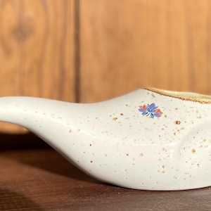 Könnte beinhalten: Weiße Keramik-Nasendusche mit braunem Rand und einem blauen und roten Blumendesign.