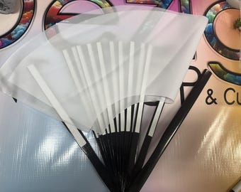 May include: A white fabric fan with black and white striped sticks. The fan is folded and has a white background with black stripes.
