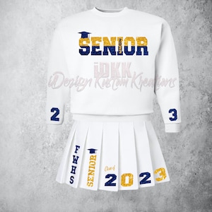 May include: White sweatshirt with the word "SENIOR" in blue and gold glitter with a graduation cap above the word. The sleeves have the numbers "2" and "3" in blue glitter. A white pleated skirt with the words "FWHS SENIOR" in blue glitter and "Class of 2023" in gold glitter.