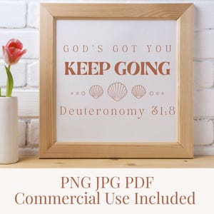 Könnte beinhalten: Ein quadratischer Holzrahmen mit einem weißen Druck, der den Text GOD'S GOT YOU KEEP GOING und Deuteronomy 31:8 in terrakottafarbenen Buchstaben enthält, akzentuiert durch drei Muschelillustrationen zwischen den Textzeilen.