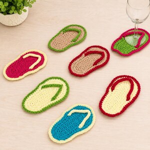 May include: A set of seven crochet coasters shaped like flip-flops in various colors including pink, beige, green, yellow, and blue. Each coaster features a textured sole and a contrasting strap, designed to protect surfaces from drinkware.
