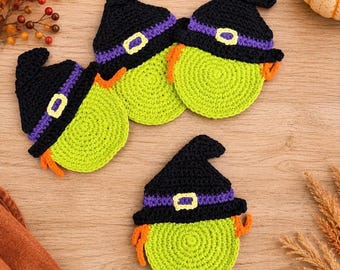 May include: Three round crochet coasters shaped like witch faces, each featuring a bright lime green circular base, orange yarn hair, and a black pointed hat with a purple band and a yellow buckle detail, crafted with visible yarn stitches.