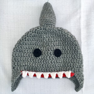 May include: Gray crocheted shark hat with black felt eyes and a red and white crocheted mouth.