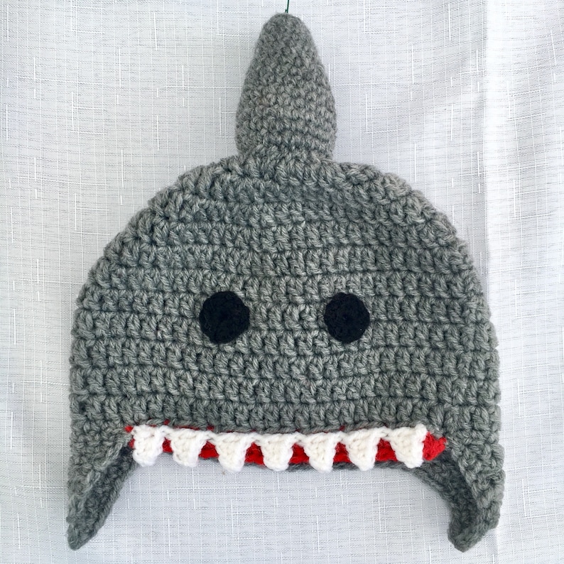 May include: Gray crocheted shark hat with black felt eyes and a red and white crocheted mouth.