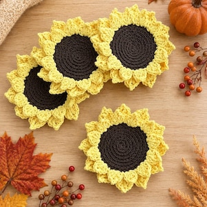 May include: Three round crochet coasters designed to resemble sunflowers, each featuring a dark brown circular center surrounded by bright yellow petals. The coasters are crafted with a textured yarn finish, showcasing a detailed stitch pattern.