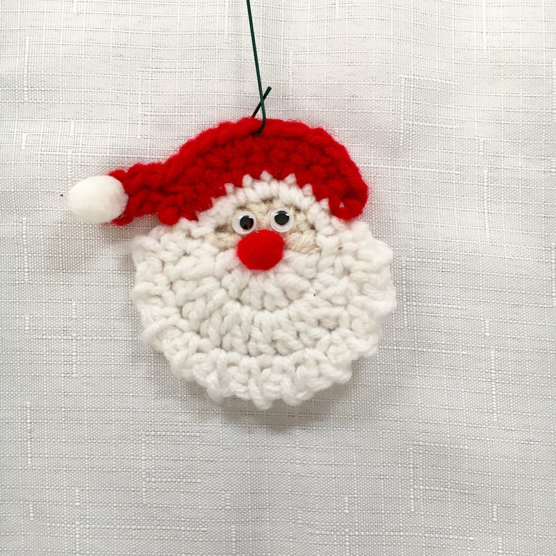 Peut inclure: Une d&eacute;coration de No&euml;l en crochet repr&eacute;sentant le P&egrave;re No&euml;l avec une barbe blanche, un chapeau rouge et des yeux globuleux.
