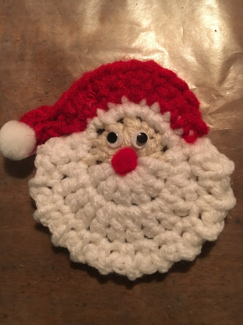 Peut inclure: Une d&eacute;coration de No&euml;l en crochet repr&eacute;sentant le P&egrave;re No&euml;l avec une barbe blanche, un chapeau rouge et des yeux globuleux.