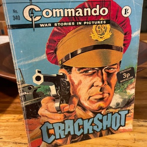 May include: A vintage Commando comic book cover featuring a soldier holding a gun with the title "Crackshot" and the text "War Stories in Pictures".