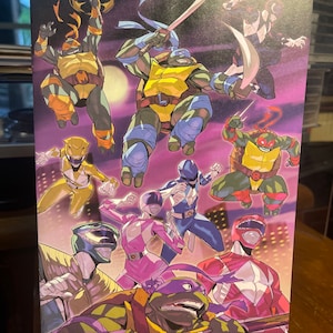 May include: A colorful illustration featuring the Teenage Mutant Ninja Turtles and the Power Rangers. The image features the four Ninja Turtles, each with their signature weapons and colors, along with the five Power Rangers, each in their signature colors and poses. The background is a purple and pink cityscape.
