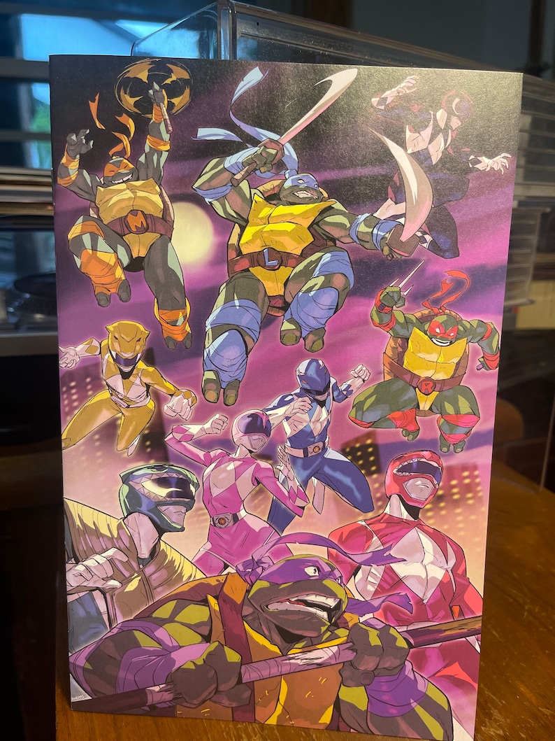 May include: A colorful illustration featuring the Teenage Mutant Ninja Turtles and the Power Rangers. The image features the four Ninja Turtles, each with their signature weapons and colors, along with the five Power Rangers, each in their signature colors and poses. The background is a purple and pink cityscape.
