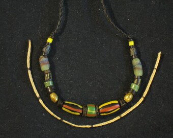 Grönt holländskt glas. Randiga svarta holländska pärlor (par). Distanser i kokosträ. Par pärlor i mässing. Svarta chevronpärlor (randiga). Halsband #12 F