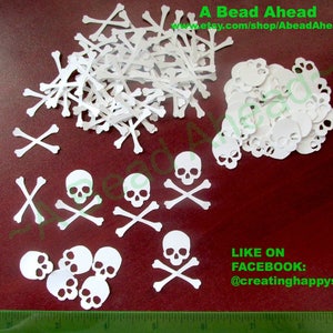 May include: White paper cutouts of skulls and crossbones, and individual bones are scattered across a surface. The image includes text that reads "A Bead Ahead" and "Like on Facebook: @creatinghappys".