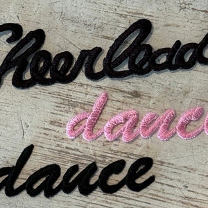 May include: Black and pink iron-on patches with the words "Cheerleader" and "dance".