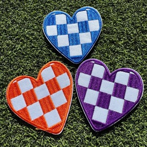 May include: Three heart-shaped patches with a checkered pattern. The patches are blue, orange, and purple.