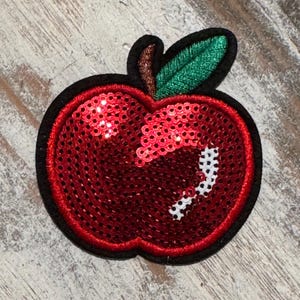 May include: Red sequin apple patch with a green felt leaf. The apple is outlined in black thread.