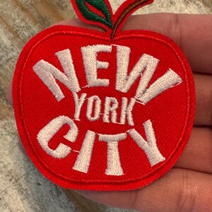 Pu&ograve; includere: Toppa a forma di mela rossa con testo ricamato bianco che recita "NEW YORK CITY".